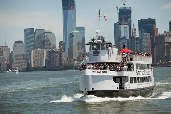 A Statue Cruise in front of the Manhattan skyline.