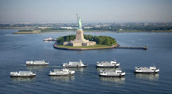 A small group of Statue Cruises surrounding the Statue of Liberty.