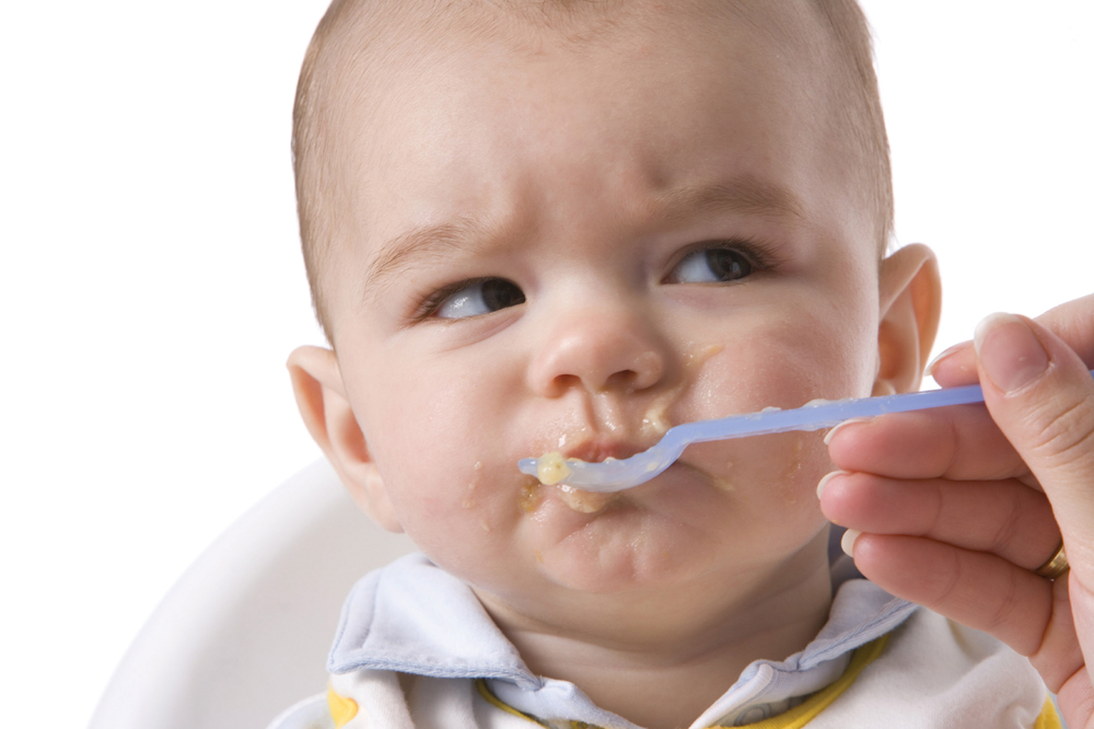 angry baby eating baby food
