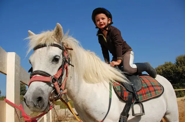 child in helmet riding horse