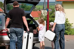 family packing the car; family vacation; parents and child preparing to travel; travelling with a special needs child