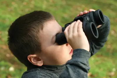 little boy looking through binoculars; child holding binoculars