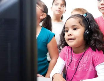 children learning by computer; little girl with headphones; learning disability