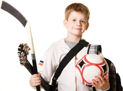 boy holding sports, music, and school equipment; well rounded child