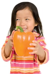 little girl holding orange pepper