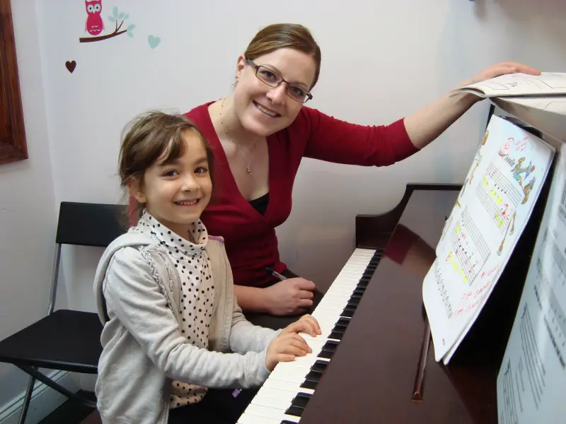 teacher and child sitting at piano